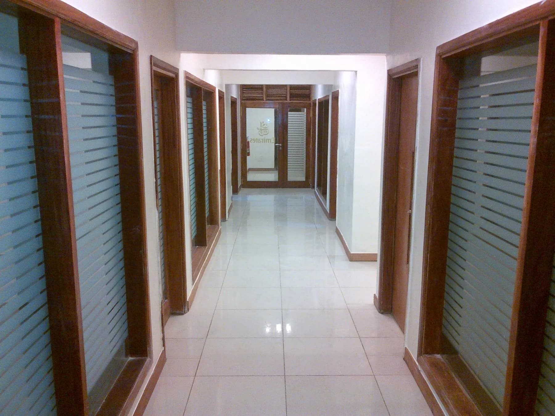 Couloir de bureaux avec cadres en bois et cloisons vitrées à bandes dépolies