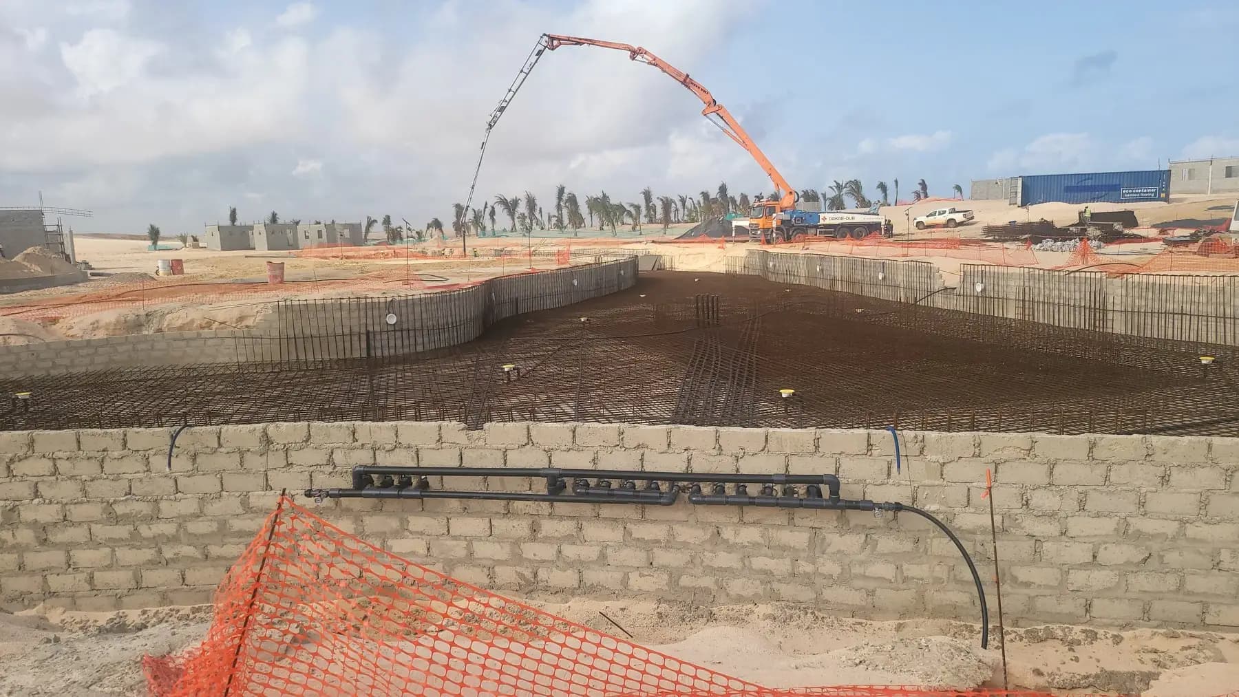 Chantier de bassin en béton armé : ferraillage du radier et pompe à béton