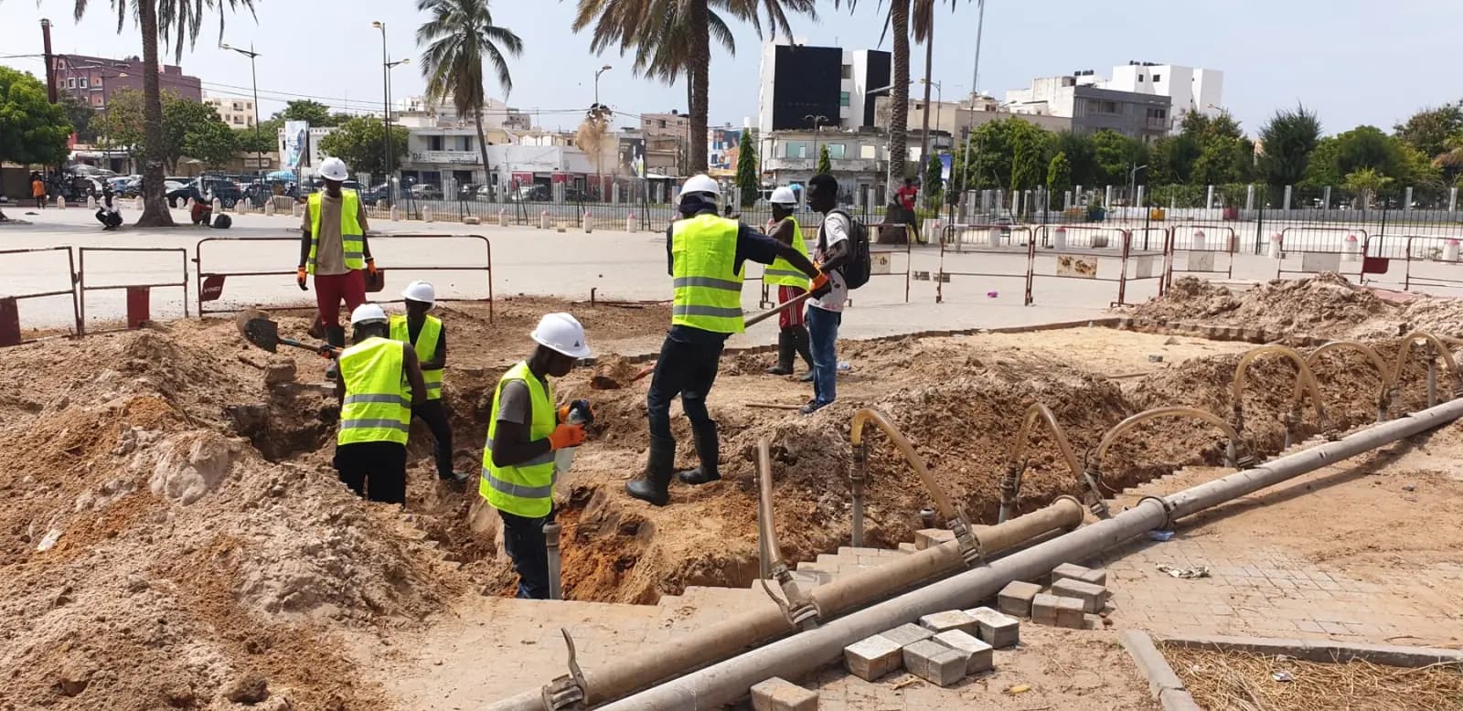 Équipe en gilets jaunes creusant une fouille pour la pose de conduites en milieu urbain